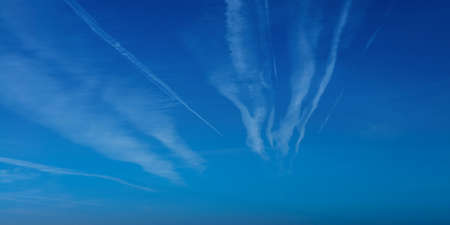 Airplane contrail against blue sky with white cloud. Jet plane condensation trail. Clouds lines made...