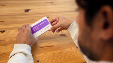 Hands of man unpacking coronavirus test kit at home. The rapid test can be done in your home with...