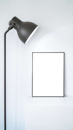 Modern panel with beautiful lamp in an office room. Minimalist black frame mockup on white background for the design of advertisements. Square frame against a wall.の写真素材
