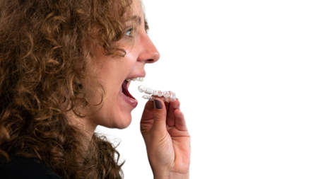 Adult woman putting transparent braces for dental correction. Caucasian person holding invisible...