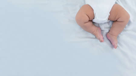 Close up of newborn boy legs on white sheet background. Baby sleeping on the bed. A beautiful conceptual image of childhood. Family and home concept with copy space.の写真素材