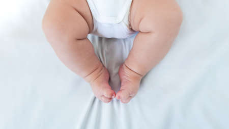 Newborn chubby legs over white background. Close up new born baby body part. Peace calm infant toddler boy laying on soft white blanket. Family maternity conceptの写真素材