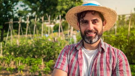 Portrait of a modern bearded farmer man looking at camera smile and stands in the agricultural...