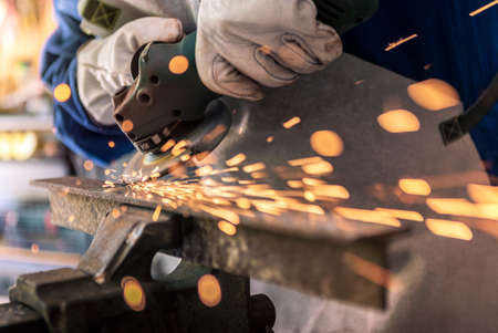 Worker grinding metal with a grinder and cleaning the steel seam. Working in a metal processing...
