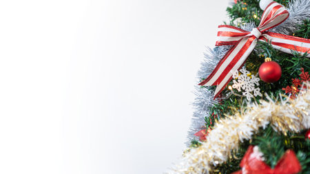 The Christmas tree branches with empty copy space for text, beautifully decorated with a Xmas red and white ribbon bow, setting a festive ambiance with the sparkling Christmas balls.の写真素材