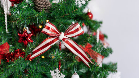 The Christmas tree branches are beautifully decorated with a Xmas red and white bow, setting a festive ambiance with the sparkling Christmas balls.の写真素材
