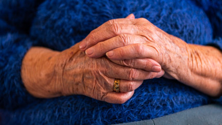 Close up elderly hands of a widowed old woman. Caucasian 90s grandma sitting at home. Wrinkled hands of the grandmotherの写真素材