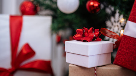 Beautiful gift boxes under a modern Christmas tree in a home background, decorated with holiday Xmas...