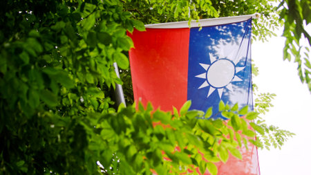 Taiwan's flag partially obscured by vibrant green leaves, creating a symbolic view of national identity and nature.の写真素材
