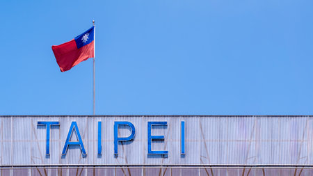 The national flag of Taiwan waving proudly against a clear blue sky in Taipei. This iconic symbol of Taiwan stands out in the city's landscape, representing national pride and identity.の写真素材