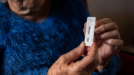 Close-up of old woman hand holding a negative test device for Covid19. Caucasian grandma showing his negative Coronavirus rapid test at home. Grandmother Quarantine pandemic.の写真素材