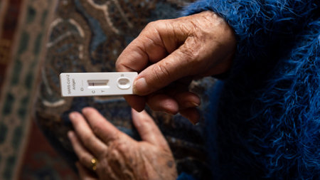 Caucasian grandma makes a rapid home test device for Covid19 virus with a negative result. Grandmother using an antigen cassette of pcr express test for new Omicron variant virus.の写真素材