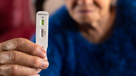 Close-up of old woman hand holding a negative test device for Covid19. Caucasian grandma showing his...