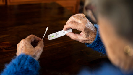 Close-up of old woman hand holding a negative test device for Covid19. Caucasian grandma showing his negative Coronavirus rapid test at home. Grandmother Quarantine pandemic.の写真素材