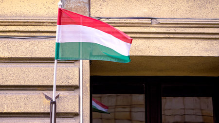 Hungarian flag billowing closeup on a building in Budapest, a symbol of national identity and heritage, captured against an urban backdrop.の写真素材