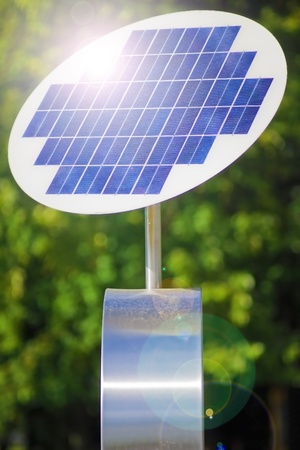 A photovoltaic solar panel with green leaves in the background の写真素材