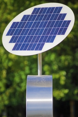 A photovoltaic solar panel with green leaves in the background の写真素材