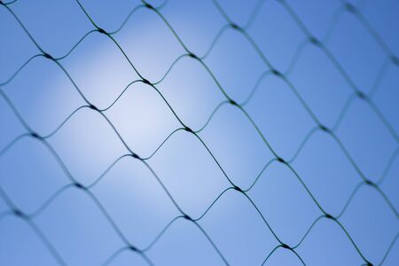 Fence on a blue sky with cloud, Mesh fence with partly cloudy sky, Chain link fence and a blue sky, fence and Blue sky background beyond. Soft focus.の写真素材