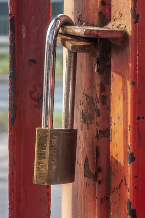 Old worn padlock locked on the paint-shabby gate. Metaphor of a liquidated business. Soft focus view.の写真素材