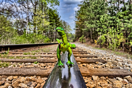 Green Velociraptor dinosaur  walking on  rail railroad tracksの写真素材