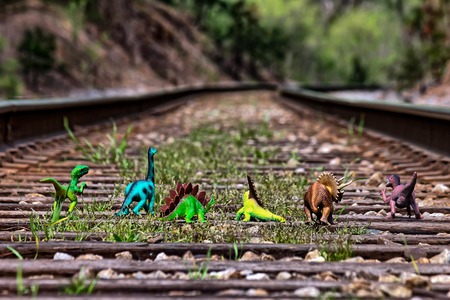 Pack of dinosaurs walking away on railroad  tracksの写真素材