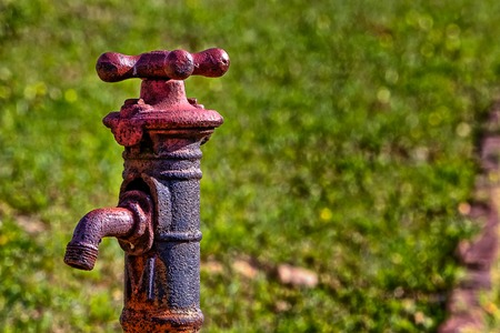 Old rusty looking faucet with grassy  backgroundの写真素材