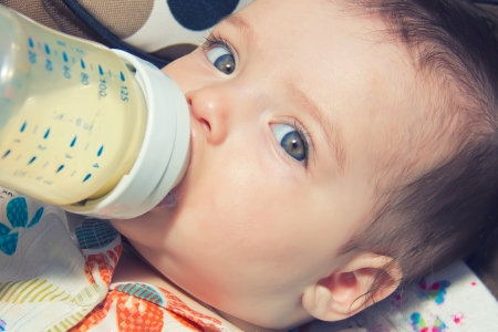 child eating out of a plastic bottleの写真素材