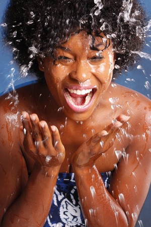 Cute African American splashes water to clean her faceの写真素材
