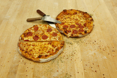 Half and half plain mozzarella and pepperoni pizza on the baker's tableの写真素材