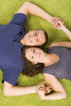 young couple lying on the green carpetの写真素材