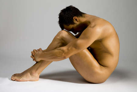 Young and muscular man sitting. He's face hide in the shadow.の写真素材