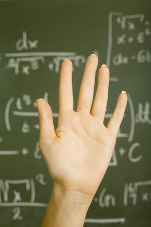 Raised hand of teenage girl in front of blackboard