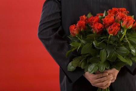 Businessman holding bouquet of roses behind his back. We don't see his face. Rear view の写真素材
