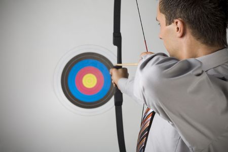 Businessman holding bow and shooting to archery target. Rear view, gray background Businessman holding bow and shooting to archery target. Rear view, gray background