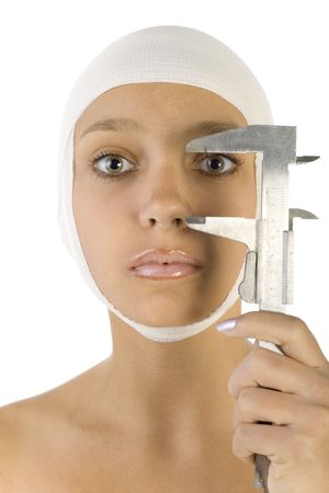 Young, beautiful woman with bandage on head and calliper in hand. Looking at camera. Front view, white backgroundの写真素材