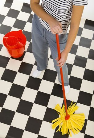 Woman standing with mop beside red bucket. View on down parts woman's body. High angle view. White...
