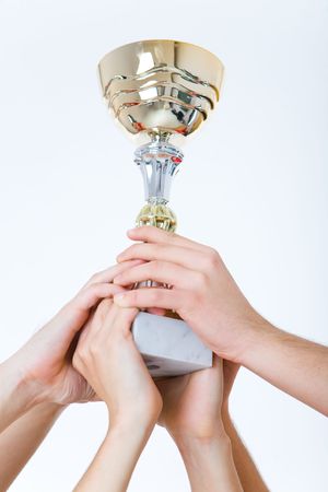 Group of men hlding a cup. Focused on hands and cup.の写真素材