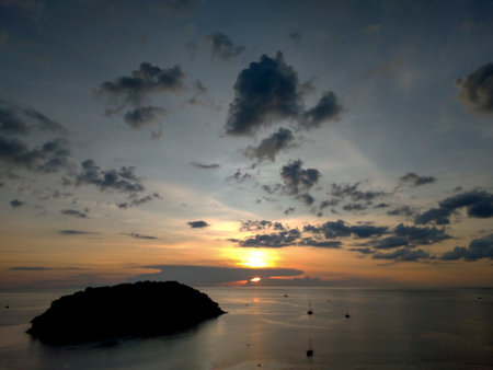 Sunset over the sea in the evening from Windmill Viewpoint in Phuket, Thailandの写真素材