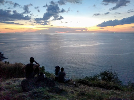 Silhouettes of People Watching Sunset from Cliff at Windmill Viewpoint, Phuket, Thailand