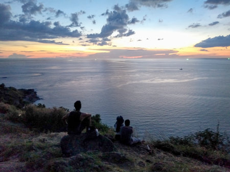 Silhouette of a man and a woman sitting on a rock and watching the sunset  at Windmill Viewpoint, Phuketの写真素材