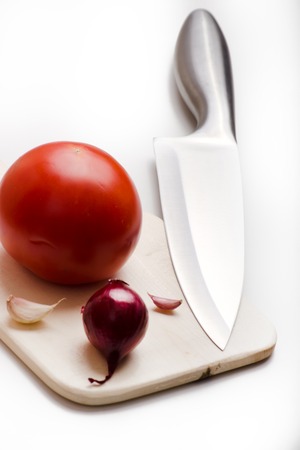 sharp kitchen instruments represented by metallic knives and fresh vegetablesの写真素材