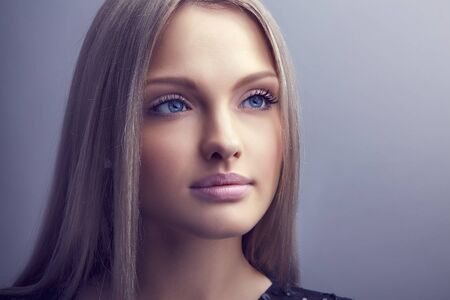 Beautiful woman face close up portrait young studio on grayの写真素材
