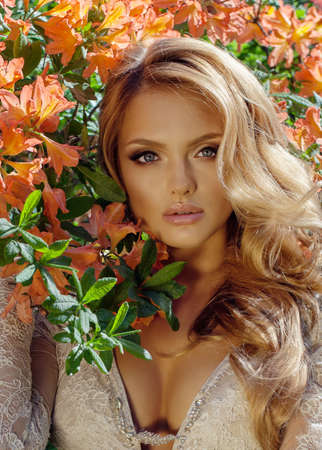 beautiful blonde bride in a luxurious wedding dress in garden with beautiful blossomの写真素材