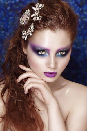 Beautiful face of a fashion model with blue eyes.Wet Curly hair. Lilac lips and bright make up. Studio portrait.の写真素材