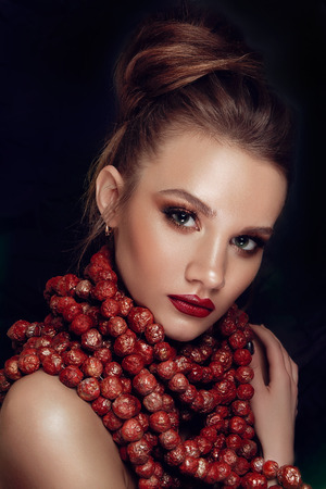 Beauty Fashion Model Girl with Perfect Make up, Long Lushes. Big Beads Necklace. Nail Art. Red Lipstick and Nail Polish. Isolated on black backgroundの写真素材