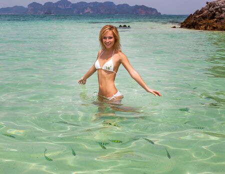 Beautiful smiling happy woman on the beach in turquoise water between feshes. Thailand.の写真素材