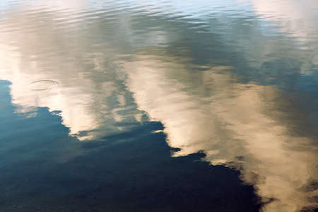 reflection of blue sky with white clouds in water, abstract background.の写真素材