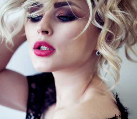 Beautiful blonde model girl with long curly hair and red lips . Fashion , beauty and make up portrait.の写真素材