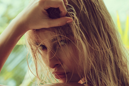 Close up portrait of blonde woman with wet hair on green sunny tropical island background. looking sensitive on a camera.の写真素材