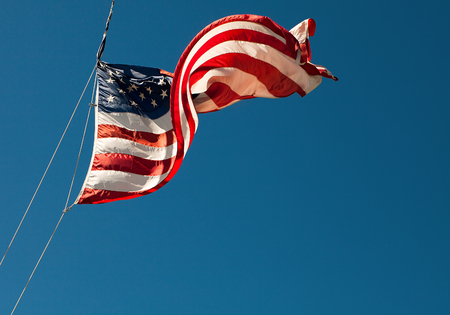 American flag blowing in the wind on the blue sky.の写真素材